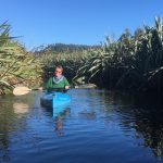 Man paddles a kayak through a narrow channel