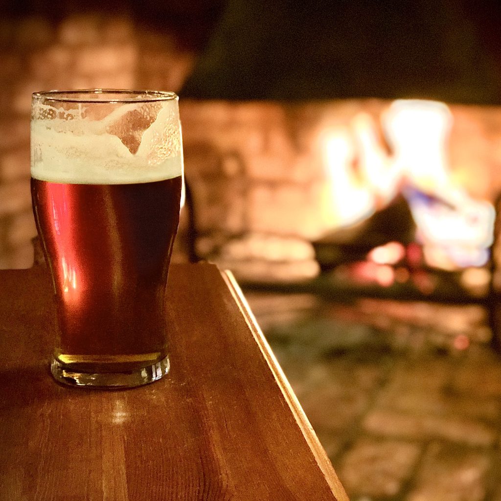 A pint sits on the bar with fire in the background