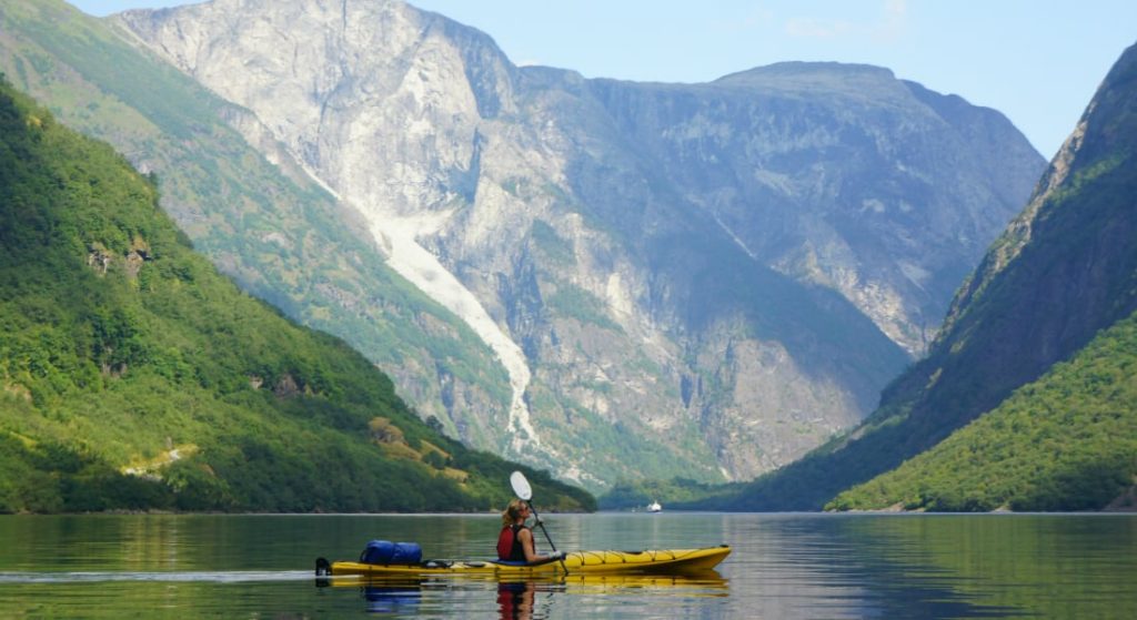 A sea kayaker sits in the middle of Aurlandsfjord