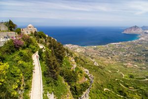 A narrow road along a ridge leads to historic Italian architecture in Erice