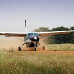 A Cessna takes off from a dirt landing strip