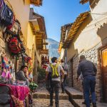 Tourists walk down a narrow street in Cusco, Peru