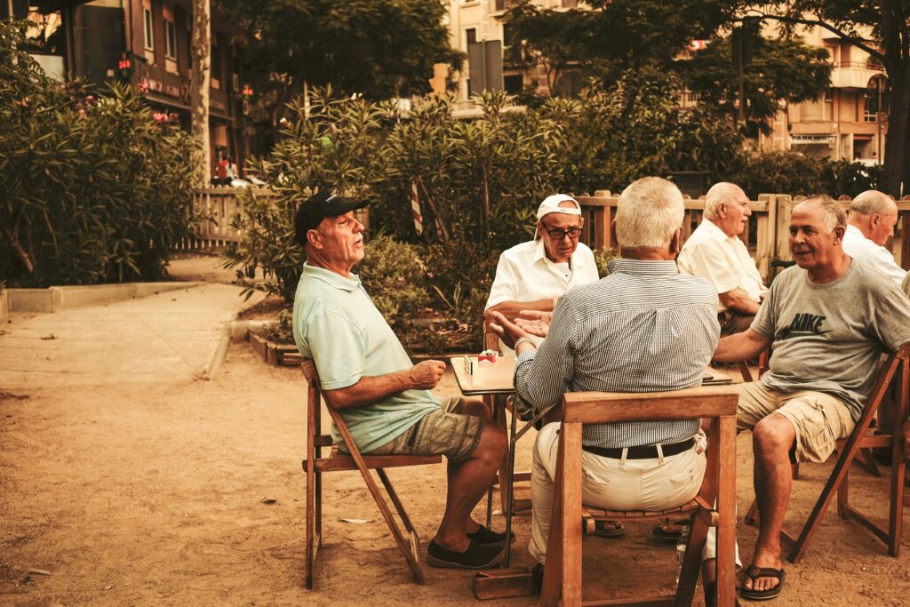 A group of older men sit around an outdoor table