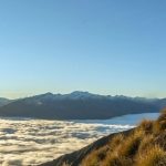 Hiker on top of a mountain above the clouds